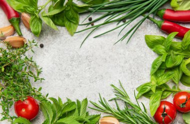 Mutfak bitkileri ve baharatlar bir çerçeve kompozisyonda düzenlenerek, gri dokulu arka planda kopya alanı sunuluyor