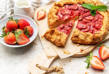 Badem gevreği ve nane yapraklarıyla süslenmiş taze pişmiş çilek galeti.