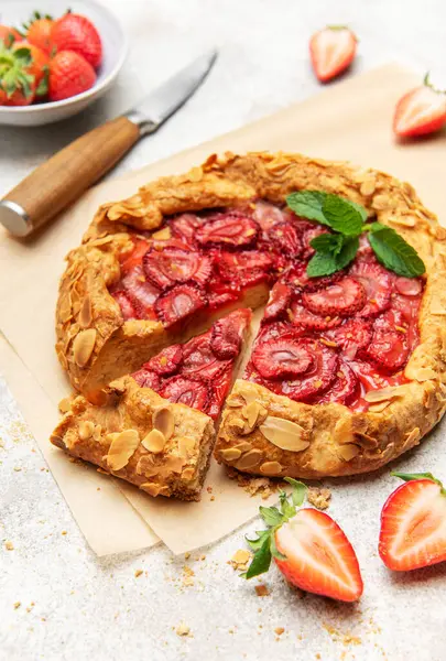 Badem gevreği ve nane yaprağı ile süslenmiş taze fırınlanmış çilek galeti, taze çilek ile servis edilir.