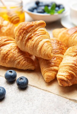 Lezzetli altın sarısı kruvasanlar yabanmersini, bal ve sütle servis edilir ve nefis bir kahvaltı hazırlar.