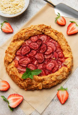 Badem gevreği ve nane yapraklarıyla süslenmiş taze pişmiş çilek galeti.