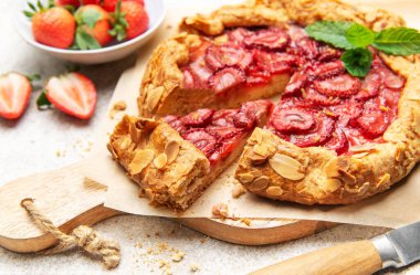 Badem gevreği ve nane yapraklarıyla süslenmiş taze pişmiş çilek galeti.