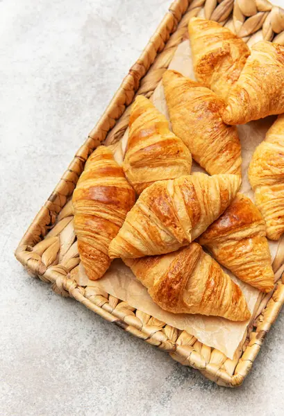 Hasır bir tepside dizilmiş altın rengi kruvasanlar cezbedici bir kahvaltı ya da kahvaltı hazırlıyor.