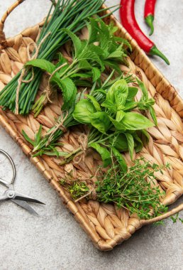 Frenk soğanı, nane, biberiye, fesleğen ve kekik gibi taze otlar hasır tepside kırmızı biberlerle birlikte oturur.