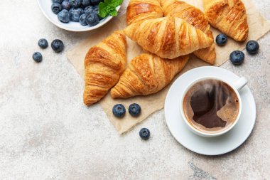 Taze pişmiş kruvasan, yabanmersini ve lezzetli bir kahvaltı hazırlayan dumanı tüten kahve.