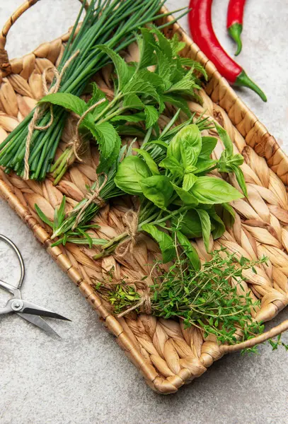 Frenk soğanı, nane, biberiye, fesleğen ve kekik gibi taze otlar hasır tepside kırmızı biberlerle birlikte oturur.