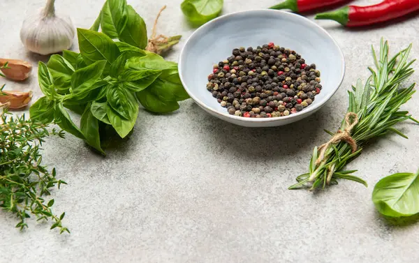 Aromatik otlar, baharatlar ve dokulu bir yüzeye dizilmiş renkli kırmızı biberler aşçılık ürünlerini geliştirmeye hazırdır.