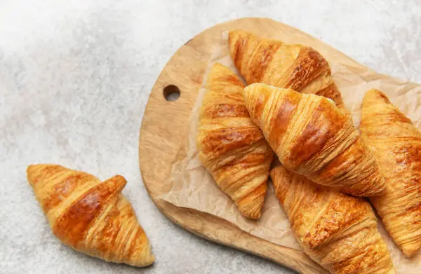 Kırsal bir tahtanın üzerinde altın kruvasanlar dinleniyor.