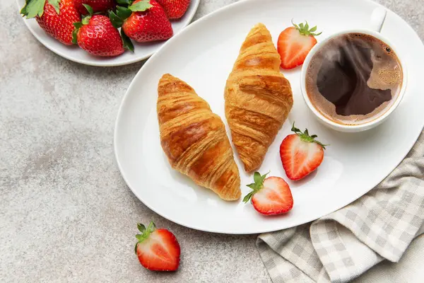 Taze kruvasan, olgun çilek ve dumanı tüten bir fincan kahvenin tadını çıkarıyorum.