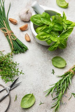 Mutfak masasına dizilmiş taze biçilmiş otlar, baharatlar ve sarımsak soğanları, mutfak yaratımlarına lezzet katmaya ve doğramaya hazır.