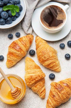 Kahvaltıda taze kruvasan, yabanmersini, bal ve bir fincan sade kahveyle servis edilir.