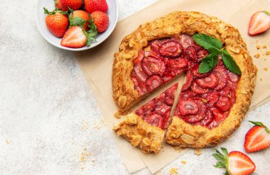 Badem gevreği ve nane yaprağı ile süslenmiş taze fırınlanmış çilek galeti, taze çilek ile servis edilir.