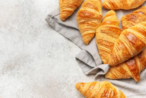 Altın sarısı kruvasanlar gri bir peçeteye dizilmiş lezzetli Fransız hamur işleri sergiliyorlar.