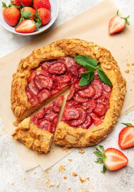 Badem gevreği ve nane yaprağı ile süslenmiş taze fırınlanmış çilek galeti, taze çilek ile servis edilir.