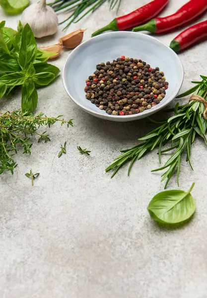 Aromatik otlar, baharatlar ve dokulu bir yüzeye dizilmiş renkli kırmızı biberler aşçılık ürünlerini geliştirmeye hazırdır.