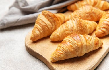 Tahtaya dizilmiş altın rengi kruvasanlar nefis Fransız hamur işleri sergiliyor.