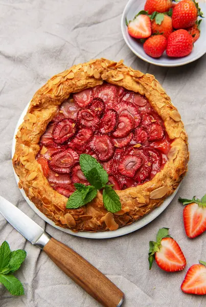 Badem gevreği ve nane yapraklı taze fırınlanmış çilek galeti taze çilek ve sütle servis edilir. Yaz tatlısı için mükemmel.