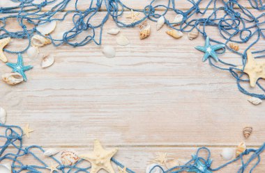 Deniz yıldızları ve deniz kabukları ile mavi balıkçı ağı kırsal ahşap arka planda bir çerçeve oluşturuyor, yaz tatili ve deniz kıyısı temaları için ideal.