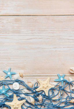 Dekoratif balık ağları, deniz yıldızları ve deniz kabuklarıyla beyaz ahşap tahtalar üzerinde yaz tatili sınırı oluşturuyorlar.