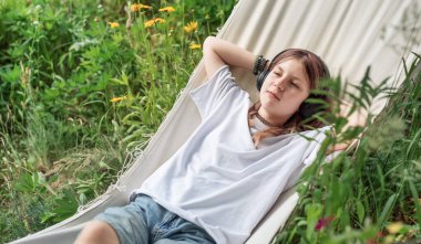 Gençler bahçede hamakta yatarken, müzik dinleyip eğleniyorlar.