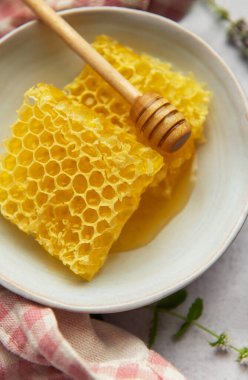 Altın bal peteği ve ahşap bal kovası bir kasede oturur, tatlı bir ikram için hazır.