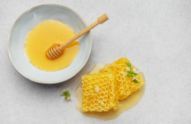 Taze bal peteği, bal peteği ve mutfak masasında bir kase bal, doğal tatlandırıcı ve sağlıklı yiyeceği temsil ediyor.