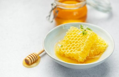 Altın bal, bal peteği ve arı poleni hafif bir arkaplanda lezzetli ve sağlıklı bir kompozisyon oluşturuyor.