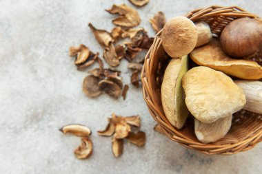 Taze toplanmış mantarlar hasır sepetten masaya dökülüyor, yanında da kurutulmuş mantar dilimleri pişmeye hazır.