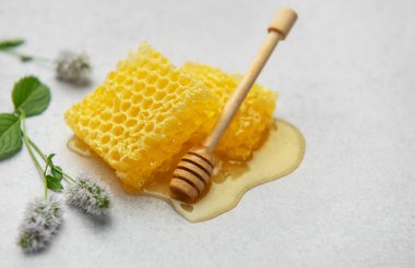 Baldan bal damlayan bal petekleri ahşap ballı ve açık arkaplanda nane çiçekleri