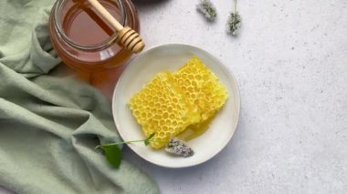 Ballı bal peteği parçaları yeşil masa örtülü beyaz bir masada.