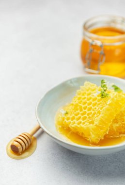 Altın bal, bal peteği ve arı poleni hafif bir arkaplanda lezzetli ve sağlıklı bir kompozisyon oluşturuyor.