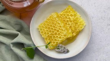 Ballı bal peteği parçaları yeşil masa örtülü beyaz bir masada.