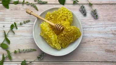 Taze bal peteği ve bal kabı ahşap bir masada üzerinde nane filizleriyle.