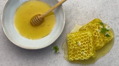 Balpeteği ve bal, beyaz bir arka planda, bir kasede bal kovanı ile düzenlenir.