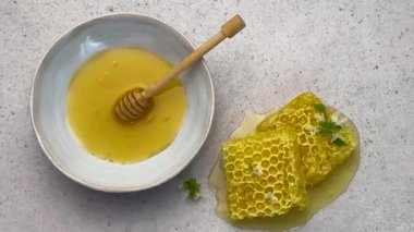 Balpeteği ve bal, beyaz bir arka planda, bir kasede bal kovanı ile düzenlenir.