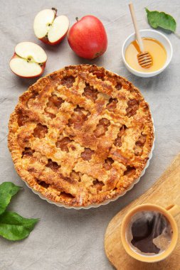 Taze pişmiş elmalı turta yanında bal ve sıcak bir sonbahar sahnesi oluşturan bir fincan buharlı kahve.