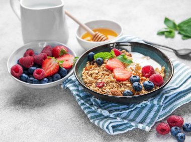 Granola ve taze meyve sağlıklı bir kahvaltı veya dokulu bir arka planda atıştırmalık hazırlar.