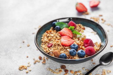 Sağlıklı bir kahvaltı için yoğurt, taze böğürtlen, badem ve nane ile dolu granola kasesi.