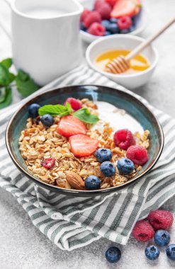 Granola ve taze meyve sağlıklı bir kahvaltı veya dokulu bir arka planda atıştırmalık hazırlar.