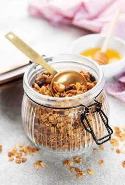 Yulaflı granola ve cam kavanozda kurutulmuş meyve, bir porsiyon altın kaşık.