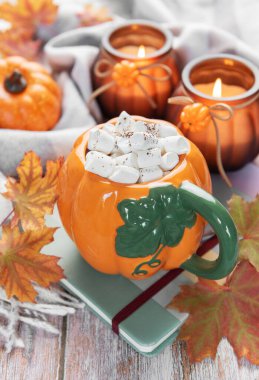 Şekerlemeli sıcak çikolata, sonbahar yaprakları ve mumlar sıcak bir sonbahar atmosferi yaratıyor.