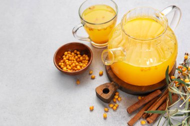 Tarçın çubukları ve taze böğürtlenlerle servis edilen cam çaydanlıktaki deniz dikenli çay.