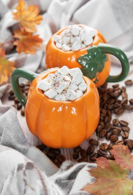 Balkabağı şeklindeki bardaklarda sıcak içecekler. Şekerlemeler, kahve çekirdekleri ve dökülen yapraklar.