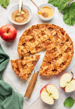 Elmalar ve fırın malzemeleriyle çevrili, dilimlenmiş taze elmalı turta.