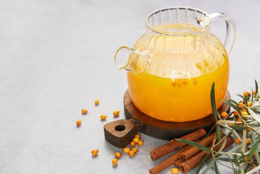 Tarçın çubukları ve taze böğürtlenlerle servis edilen cam çaydanlıktaki deniz dikenli çay.