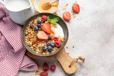 Granola with yogurt, strawberries, blueberries, raspberries, and almonds for a healthy start