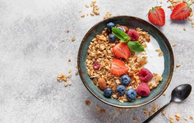 Sağlıklı bir kahvaltı için yoğurt, taze böğürtlen, badem ve nane ile dolu granola kasesi.