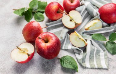 Çizgili yeşil ve beyaz kumaş üzerinde yaprakları olan kırmızı elmalar ve elmalar.