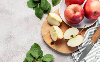 Kırmızı elmalarla birlikte bir bıçak ve yıpranmış arka planda yapraklar.