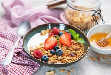 Bir kase granola ve taze meyve ve bademle kaplı yoğurt.